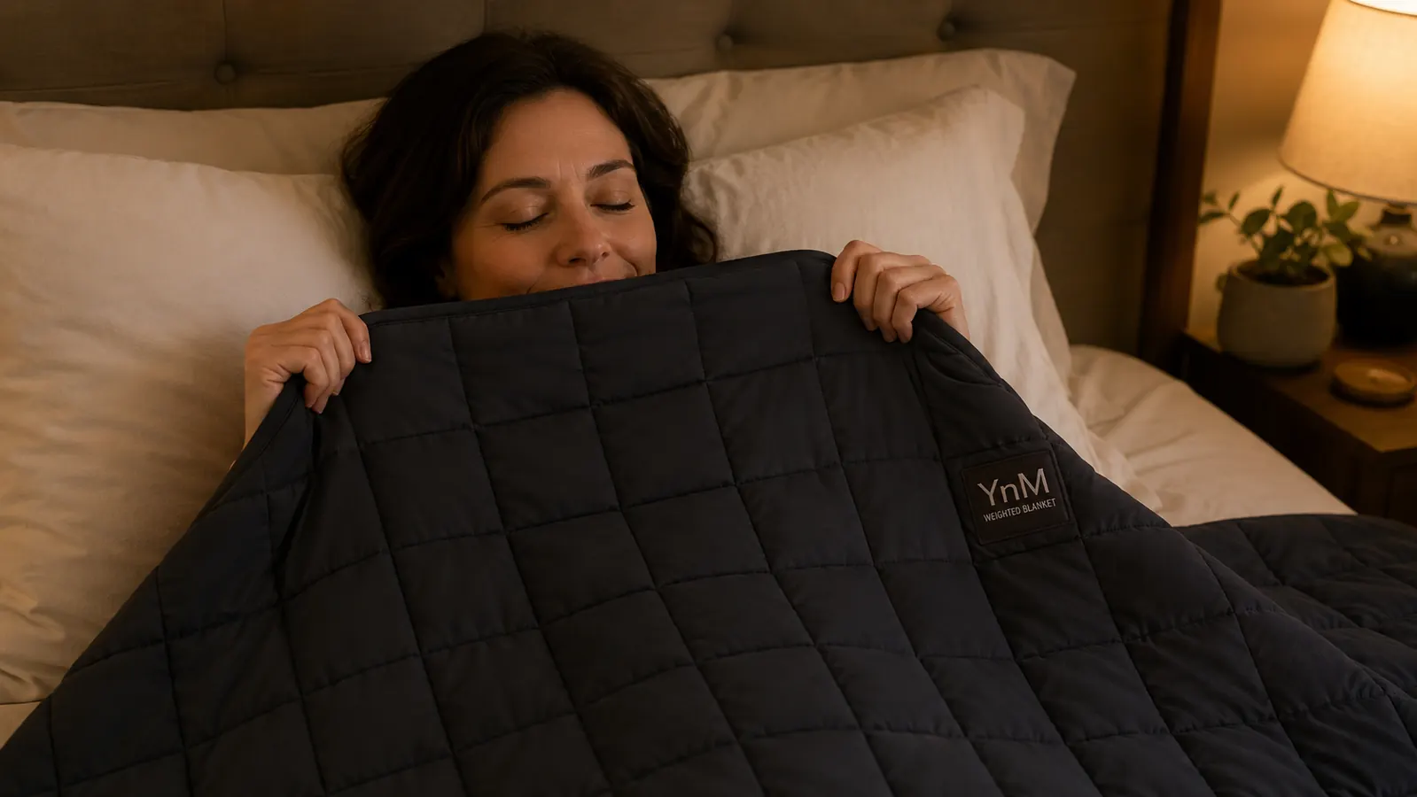 YnM weighted blanket folded on a bed showing the quilted grid pattern and glass bead fill